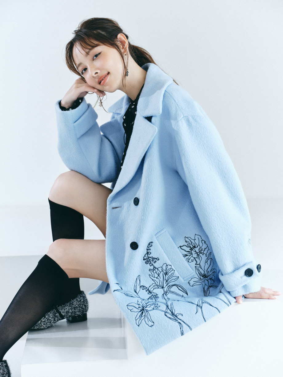 エンブロイダリーコクーンコート＆クレープラッフルフリルブラウス＆ボンディングミニスカート＆シアーレースハイソックス＆ストラップ付フラットパンプス＆LBロゴイヤリングを着た女性