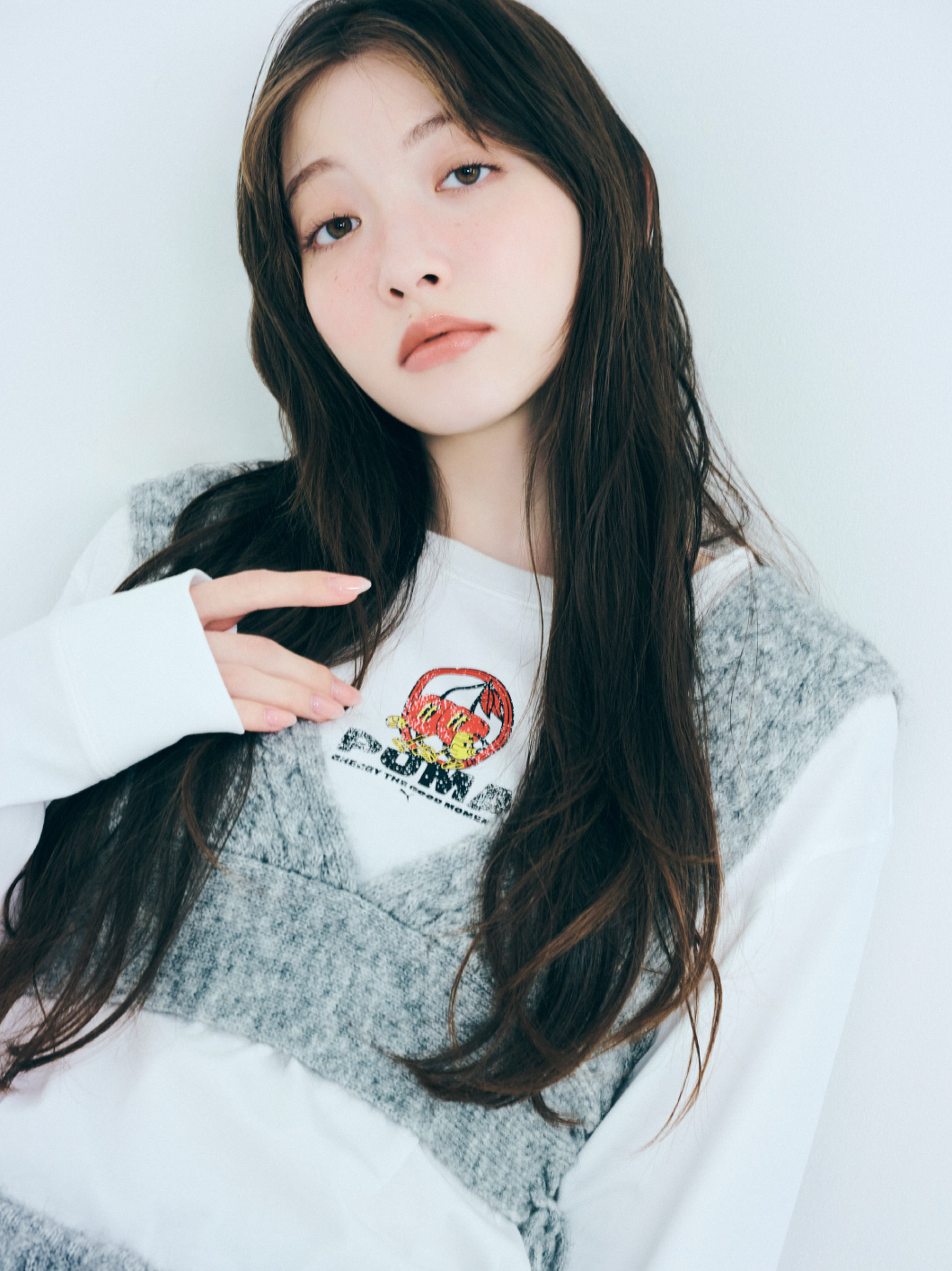 ロングTシャツ、ベスト、スカート、バッグ、靴下、靴を着用した女性