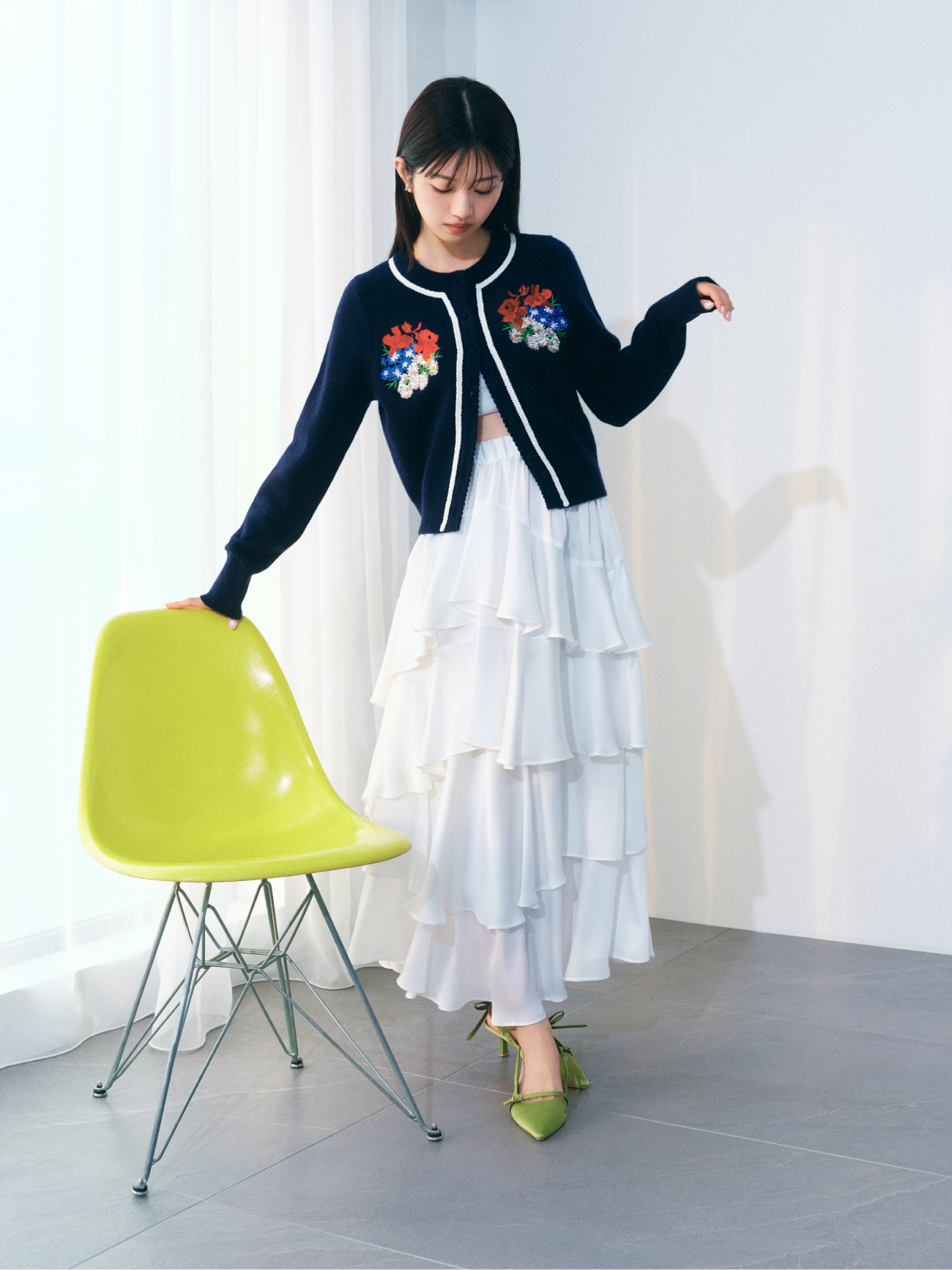 ネイビーのフラワーモチーフカーディガン・白のスリットティアードスカート・グリーンのリボンスリングバックパンプス・金のLILY BROWNロゴピアスの着用例