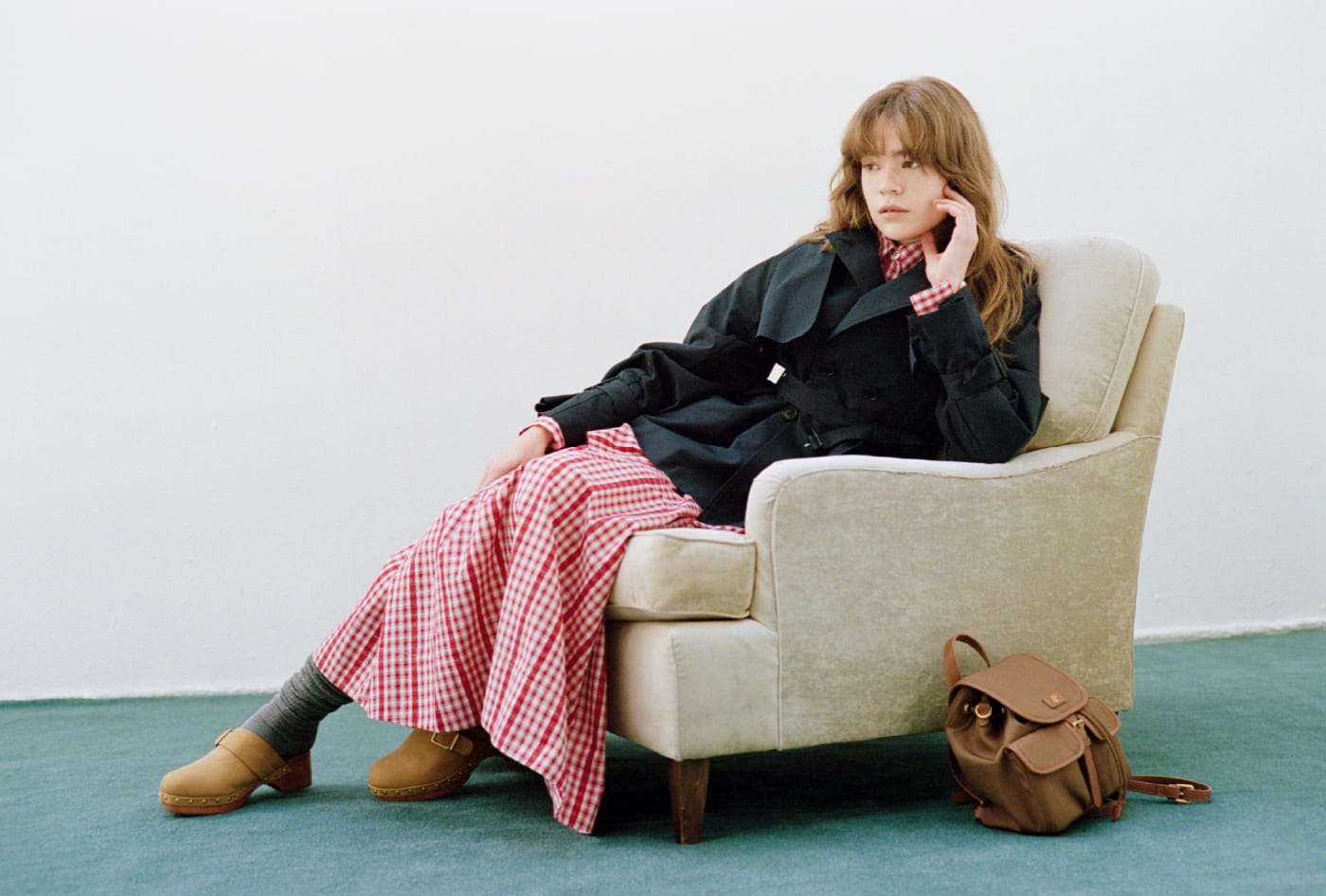 love クラシックミドルトレンチコート＆Lily Bearレターモチーフバリエシャツ＆２wayボリュームシャツスカート＆2wayバックパック＆ウッドソールスタッズサボを着用した女性