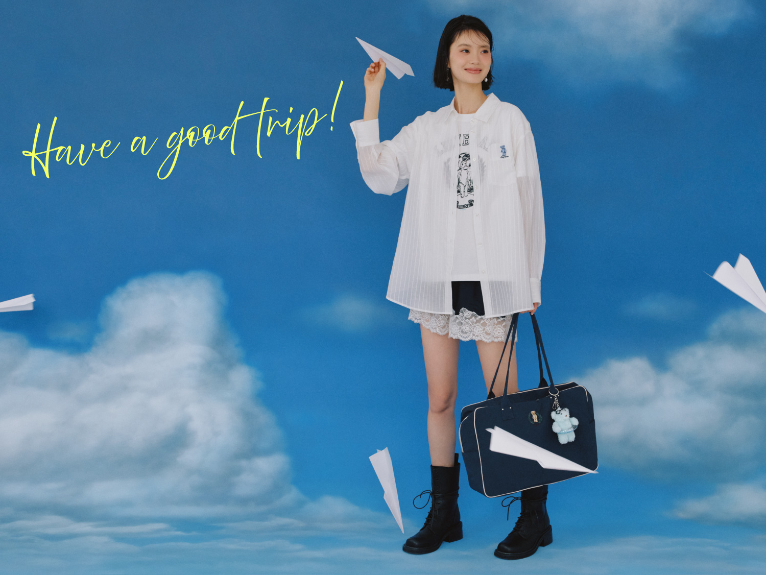 白のシアーシャツとTシャツ・ネイビーのサテンランジェリーショートパンツ・ダークネイビーのボストンバッグ・チャーム・ピアス・黒のレースアップショートブーツを合わせたコーディネート