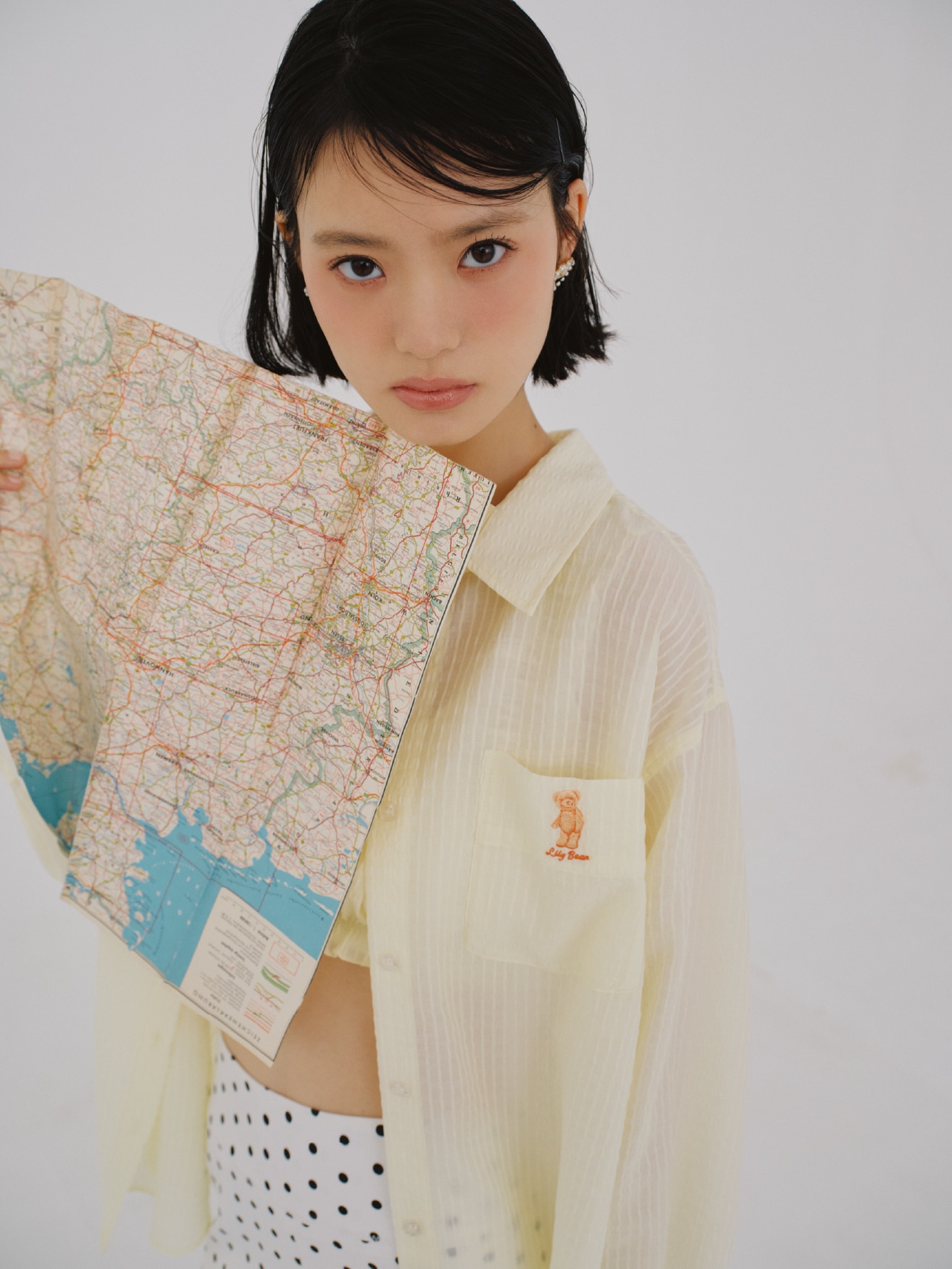 イエローのシアーシャツとシアーストライプシャーリングビスチェ・ドット柄のマイクロショートパンツ・ピアスを合わせたコーディネート