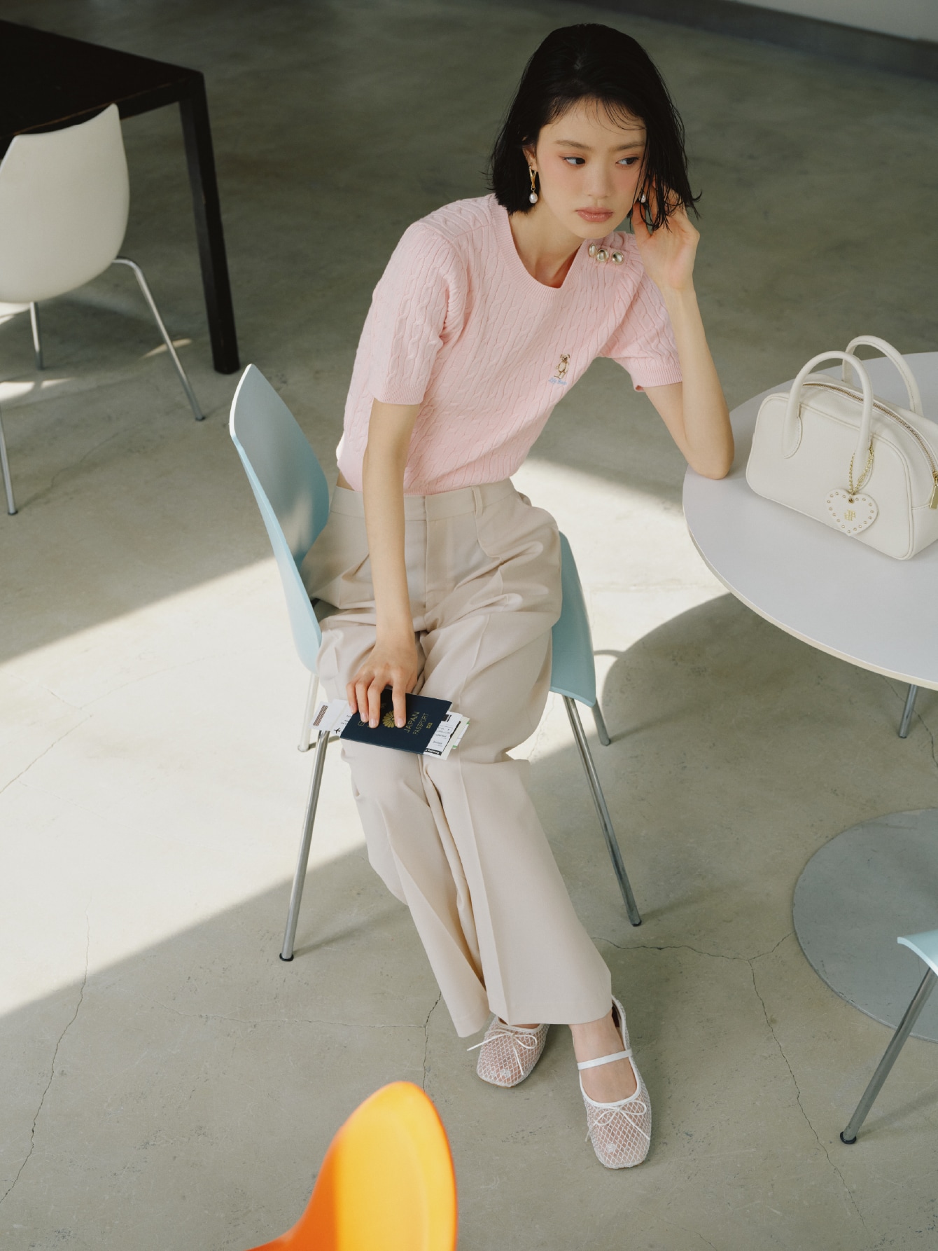 ピンクのサイドボタンケーブルニット・アイボリーのワイドパンツとボストンバッグ・ピアス・白のバレエシューズを合わせたコーディネート