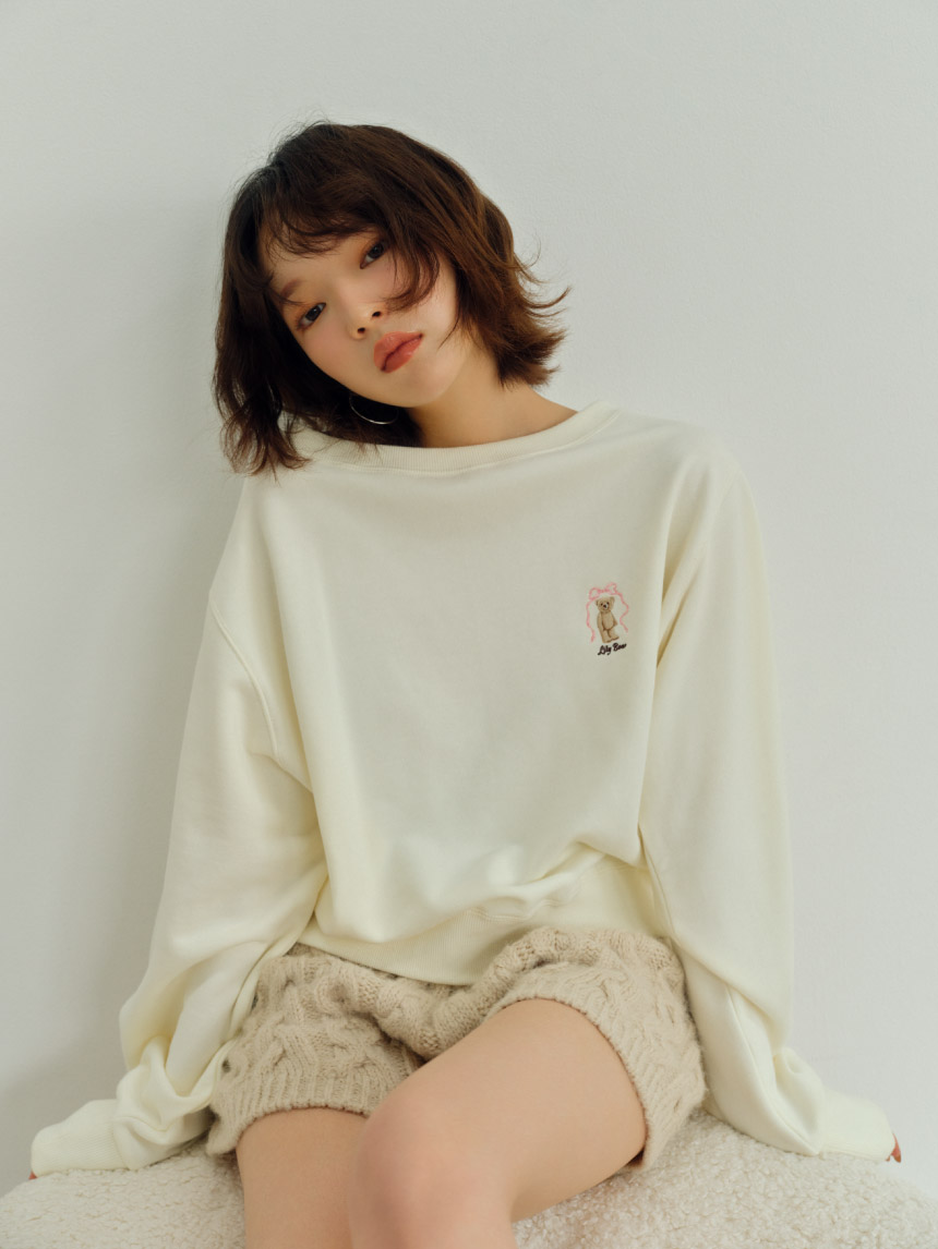 バリエーションニットショートパンツ・【WEB限定カラー】Lily Bearリボンスウェット・トップハンドルファーバッグ・バックルメリージェーン・スリットレッグウォーマー・ハートフープピアスを着用した女性