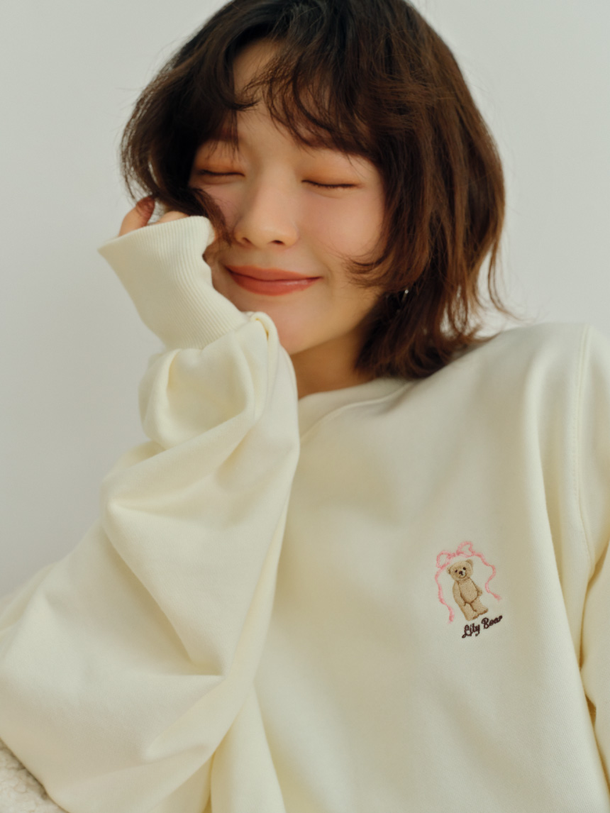 バリエーションニットショートパンツ・【WEB限定カラー】Lily Bearリボンスウェット・トップハンドルファーバッグ・バックルメリージェーン・スリットレッグウォーマー・ハートフープピアスを着用した女性