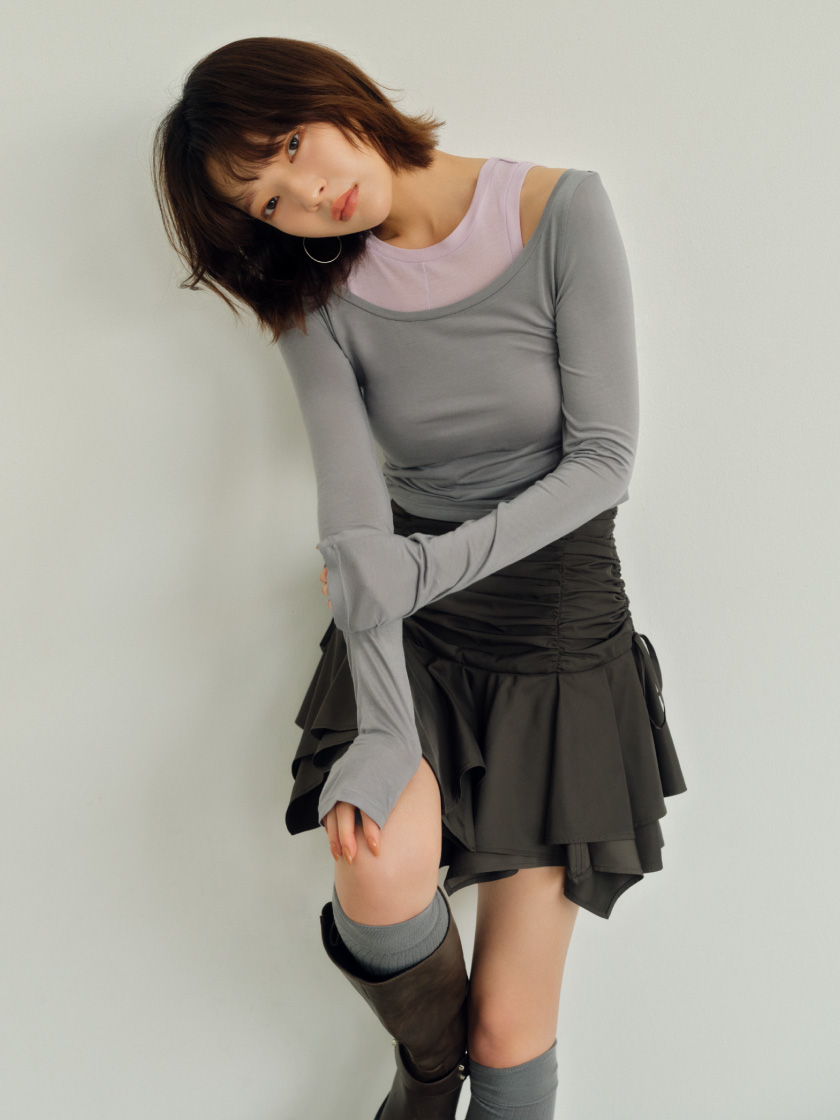ランダムヘムギャザーミニスカート・レイヤードセットカットソー・バイカーブーツ・リブニーハイソックスを着用した女性