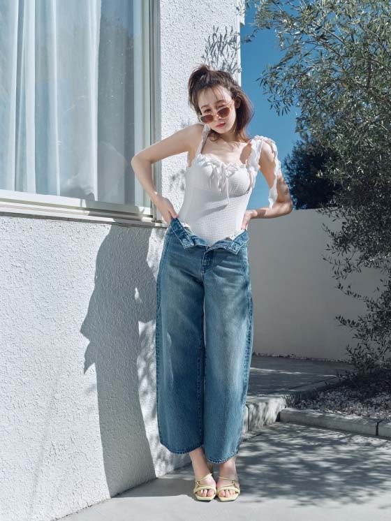 白の水着にジーンズを履いた女性がサングラスをつけて正面を向いている全身画像